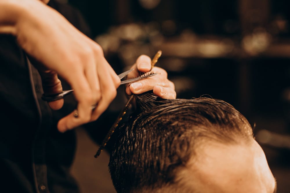 Barber cutting a client's hair with scissors